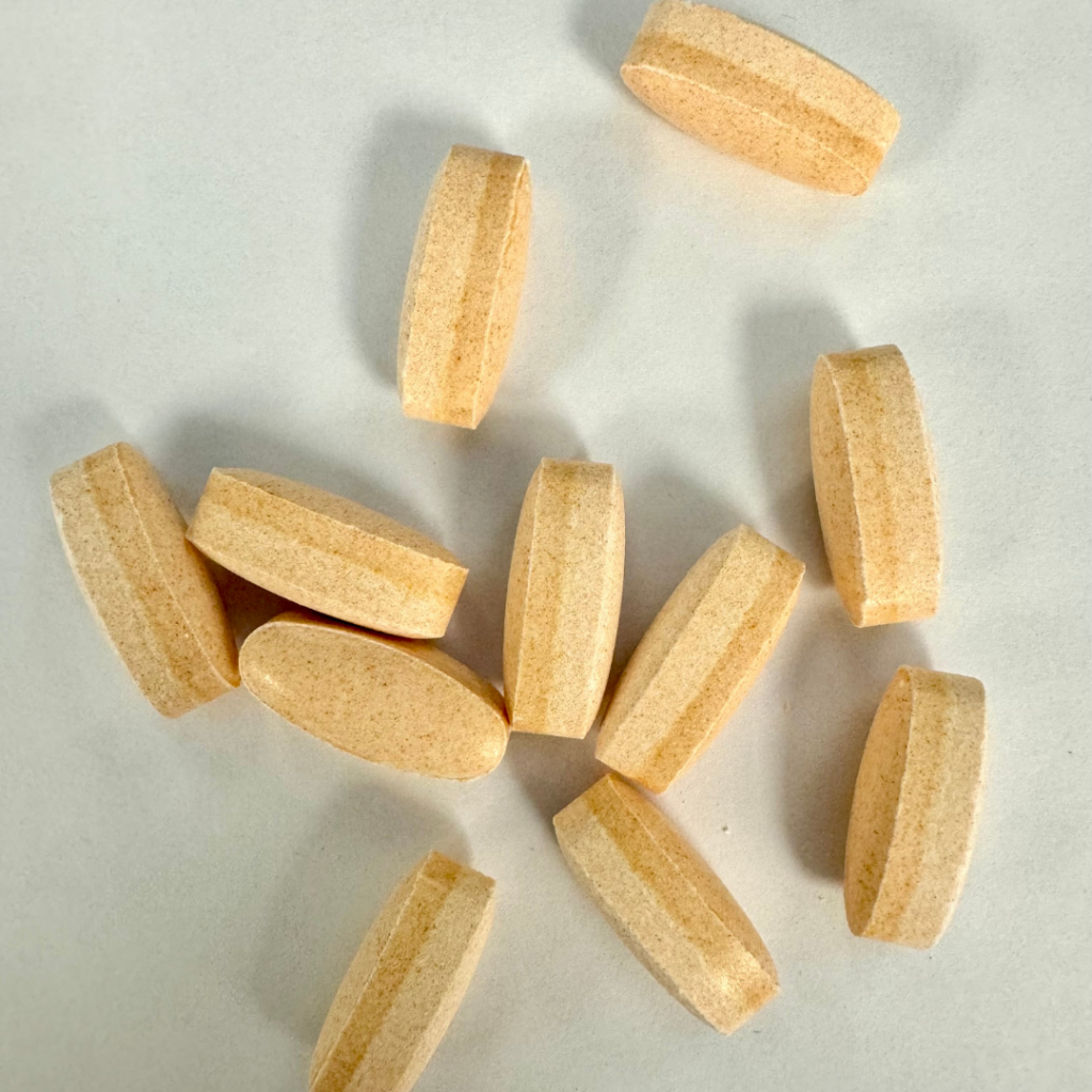 A precise stack of uniform tan nutritional tablets, highlighting consistent compression and impeccable manufacturing quality.